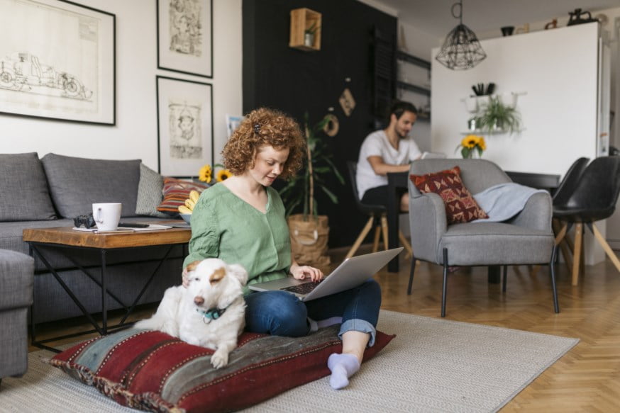 Dame med PC sitter på gulvet sammen med en hund